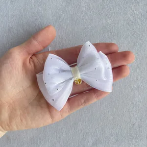 Close-up of white tulle bow with silver rhinestones and a small golden bell detail