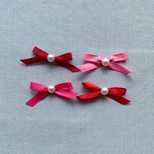 Detailed view of satin ribbon bows with faux pearl centers in four assorted colors