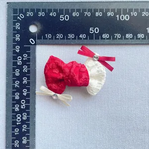 Dettaglio di un fiocco in pizzo rosso e bianco con strass, misura 45mm su righello
