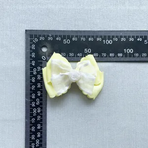 Detail shot of yellow layered bow accessory with resin rose and size measurement scale