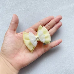 Detailed view of a mini tulle bow with sequins and a gold star held in hand for size