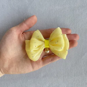 Macro view of layered yellow organza bow with sequins and a pearl pendant charm