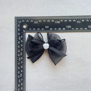 Makroaufnahme von 10,5cm schwarzer Chiffonschleife mit weißer Harzrose und Linealmaß