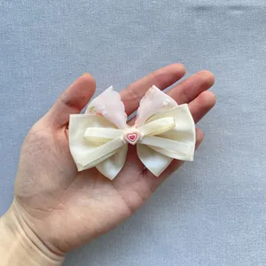 Detail of floral chiffon and satin handmade bow with a pink heart charm