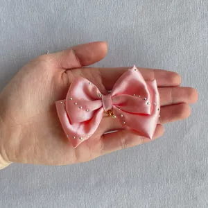 Detailed view of handmade pink satin bow with sparkling silver rhinestones for hair DIY