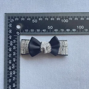 Close-up of handmade tweed fabric hair clip with a black satin bow and 7.5cm scale