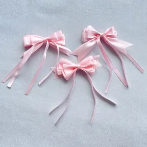Trois nœuds en satin rose pâle avec de longs rubans sur un tissu texturé bleu clair