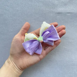Close-up of handmade floral bow clip with purple ribbon and resin strawberry detail