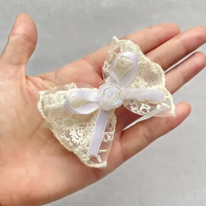 Detail view of handmade beige lace bow with resin rose held in hand to show small size