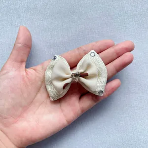 Handheld view of cream bow accessory with sparkling heart crystal and rhinestones