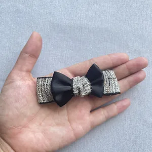 Detail of tweed and black satin bow hair clip with textured weave and metal clip