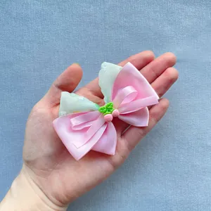 Detailed view of pink satin bow with floral pattern fabric and cute strawberry charm