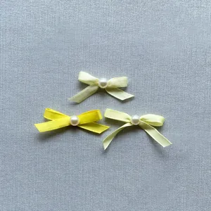 Detail of satin bow cake toppers with pearls in bright yellow and cream tones