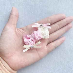 Dettaglio di un fiocco in pizzo rosa fatto a mano con strass tenuto nel palmo della mano