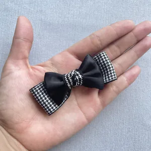 Detail of handmade double-layered bow accessory with black satin and houndstooth pattern
