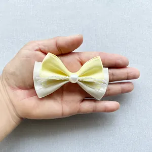 Macro detail showing yellow and beige satin bow with a large pearl and lace center