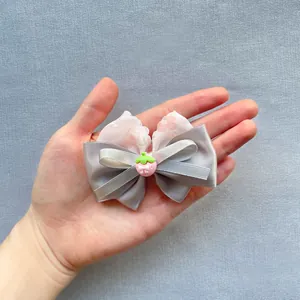 Detailed view of a handmade floral bow accessory with pink strawberry resin center decoration