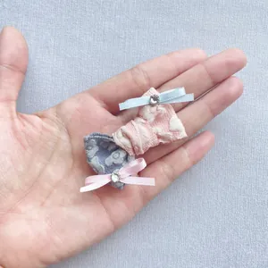 Dettaglio di due mini fiocchi in tessuto fatti a mano con strass per capelli e bambole
