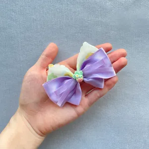 Detail of a floral purple ribbon bow with strawberry resin charm for hair accessories
