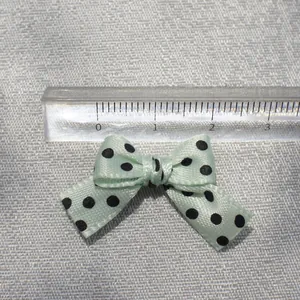 Polka dot fabric bow in mint green with black dots, 3cm size shown on a ruler scale