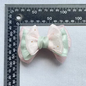 Dettaglio del fiocco in organza rosa e nastro verde con perline su scala di 85 mm