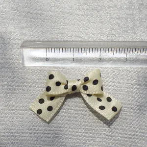 Close-up of 3cm white polka dot bow accessory with ruler showing precise width