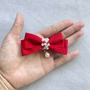 Detailansicht einer roten Schleife mit Perlenverzierung und goldenem Anhänger für DIY