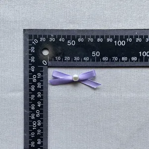 Detail view of a 35mm purple ribbon bow with a white pearl bead for cake decoration
