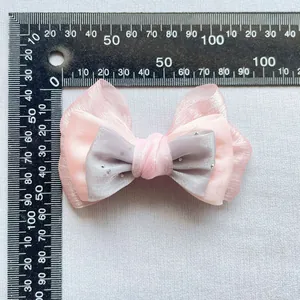 Vista dettagliata del fiocco rosa e grigio con strass e righello di misurazione
