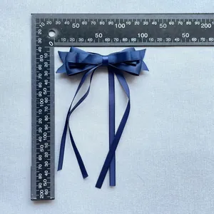 Détail d'un nœud en satin bleu marine avec de longs rubans et une règle de mesure