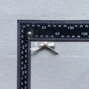 Macro view of a 30mm handmade satin ribbon bow with a pearl center for cake decoration