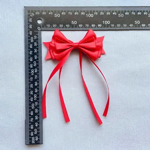 Détail d'un nœud en satin rouge avec de longs rubans à côté d'une règle graduée