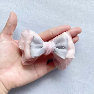 Vista macro del fiocco fai-da-te in organza rosa e raso grigio con perline d'argento