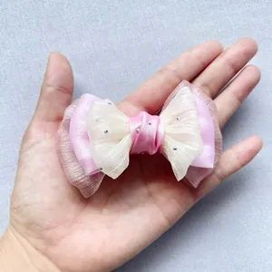 Dettaglio del fiocco in garza a doppio strato rosa e bianco con strass argentati