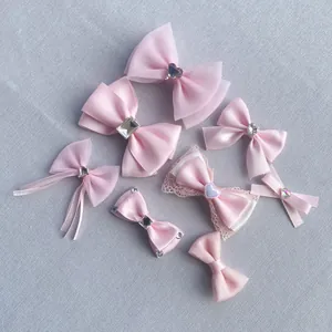 Flat lay of pink satin and organza bow hair clips with crystal heart embellishments