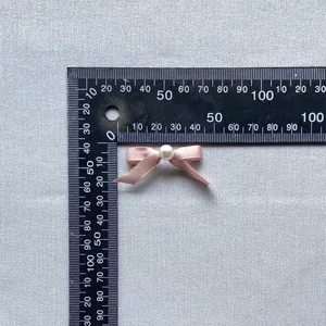 Macro shot of 30x20mm pink satin bow with faux pearl detail for cake and DIY decor