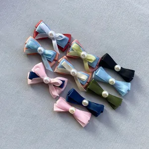 Detalle de 9 pinzas de lazo de satén hechas a mano con perlas en colores variados