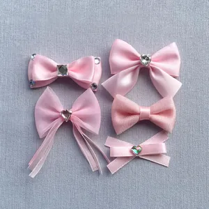 Detail view of pink satin and mesh bow accessories with rhinestones and long ribbons