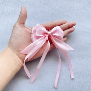 Détail d'un nœud en satin rose multicouche fait main avec de longs rubans pendants