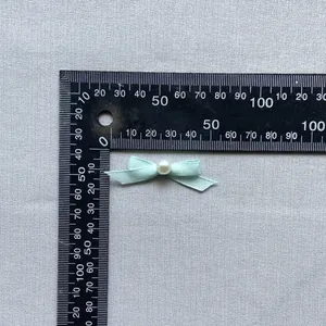 Detail of 40mm light blue satin bow with center pearl for DIY crafts and cake decor
