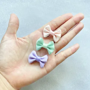 Detailed macro view of 3cm mini satin ribbon bows in pastel pink, green and purple