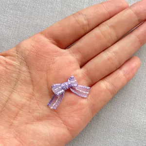 Detailed macro view of 1.5cm lilac mini bowknot accessory held in hand for scale