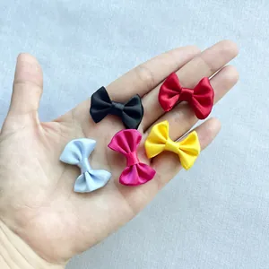 Close-up of mini handmade colorful satin bows held in hand for DIY accessory size reference