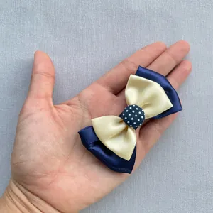 Détail d'un nœud en satin double couche de 7,5cm bleu marine et beige tenu à la main