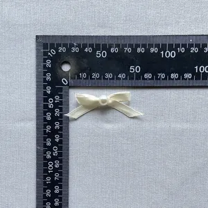 Close-up of a 4cm off-white satin bow with center pearl for cake and fashion decor