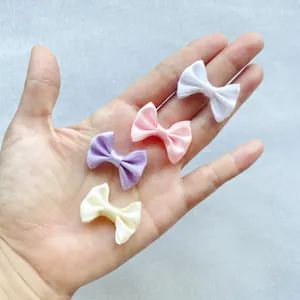 Handheld view of mini 3cm satin ribbon bows in white, pink, beige and purple pastel colors