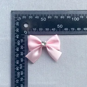 Pink satin ribbon bow with heart rhinestone detail and 40mm size measurement