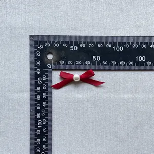 Close-up of red ribbon bow with white pearl for cake decoration and crafts