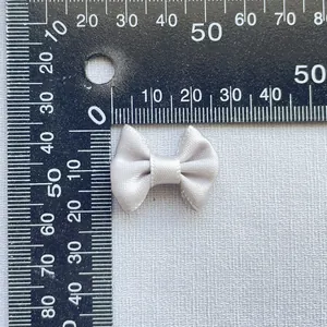 Silver-grey satin bow accessory measured on a ruler for DIY crafts and hair accessories