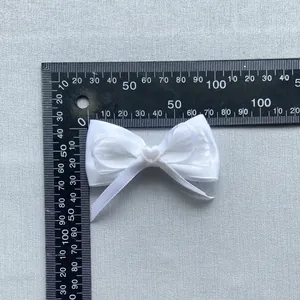 Detail van witte satijnen en organza DIY-strik met hartvormige parel en maatliniaal